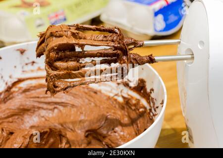 Pastella per torta al cioccolato in un recipiente con un closeup del miscelatore elettrico, Regno Unito Foto Stock