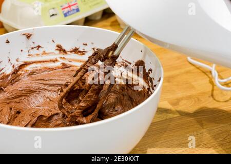 Pastella per torta al cioccolato in un recipiente con un closeup del miscelatore elettrico, Regno Unito Foto Stock