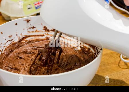 Pastella per torta al cioccolato in un recipiente con un closeup del miscelatore elettrico, Regno Unito Foto Stock