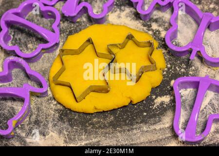 La taglierina per biscotti a forma di stella forma e l'impasto all'interno sul nero tagliere Foto Stock