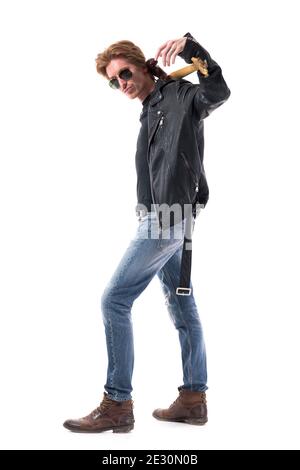 Vista laterale del bel rocker macho con atteggiamento che porta la chitarra sulla spalla. Corpo intero isolato su sfondo bianco. Foto Stock