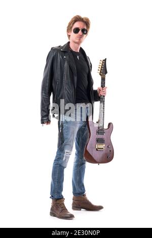 Chitarrista maschile in stile rocker alla moda che tiene la sua chitarra elettrica guardando la macchina fotografica. Corpo intero isolato su sfondo bianco. Foto Stock