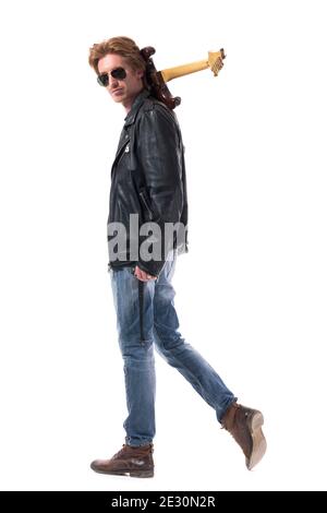 Vista laterale del sicuro rocker macho con occhiali da sole che portano la chitarra elettrica. Corpo intero isolato su sfondo bianco. Foto Stock
