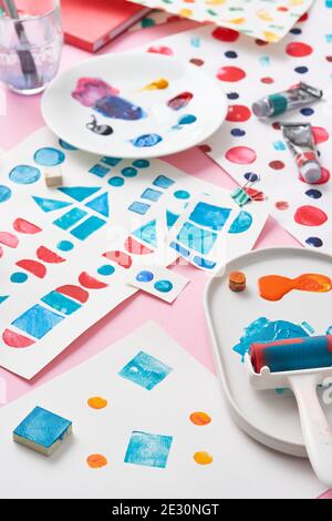 Fogli di carta con vari ornamenti geometrici stampati e pittura assortita strumenti posizionati su sfondo rosa Foto Stock