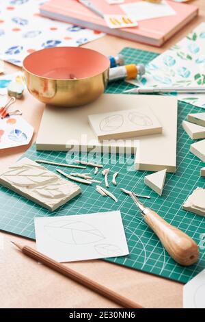 Francobolli di gomma scolpiti posti sul tavolo vicino alla ciotola e alla carta fogli con motivi a lamelle Foto Stock