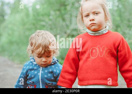 sorella e fratello camminano per la strada in un piccolo villaggio tra le case Foto Stock