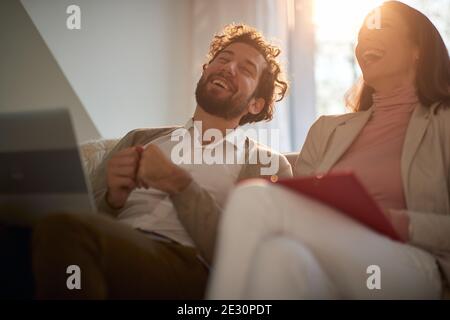 Giovane coppia felice di affari ama lavorare da casa in un'atmosfera rilassata. Affari, persone, lavoro da casa Foto Stock