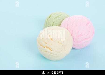 Primo piano di vari deliziosi cucchiai di gelato aromatizzati isolati su sfondo blu Foto Stock