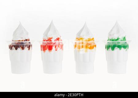 Shot di crema per closeup di gelato morbido con guarnizioni aromatizzate in coppe trasparenti Foto Stock