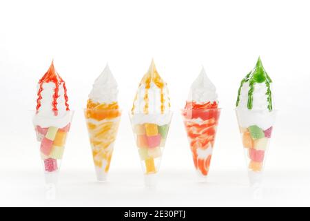 Shot di crema per closeup di gelato morbido con guarnizioni aromatizzate e frutta in tazze trasparenti Foto Stock