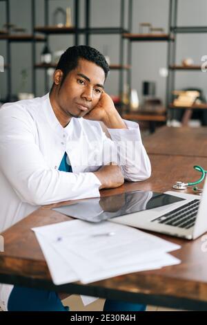 Stressato Africano Americano uomo nero medico guardando la lettura del portatile cattive notizie online Foto Stock