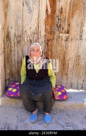 SELIME, AKSARAY, TURCHIA-LUGLIO 22: Old Village Woman in posa accanto alla sua casa door.July 22,2017 a Selime, Aksaray, Turchia. Foto Stock