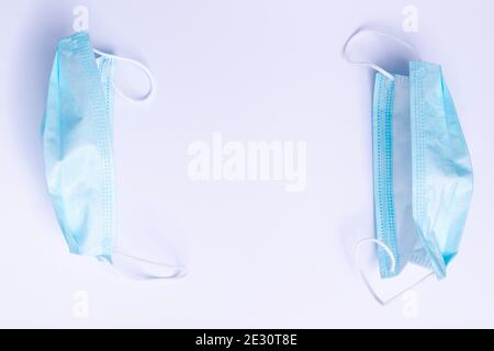 Due maschere mediche monouso su sfondo bianco con uno spazio vuoto al centro. Foto Stock