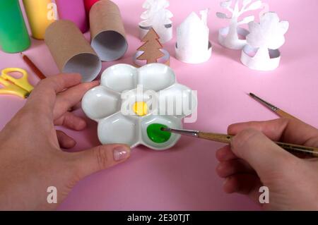 Come fare alberi, decorazione. Attività quotidiane, fai da te per i bambini, zero sprechi, giocattoli ecologici fatti a mano da rotolo di carta. Colori sulla tavolozza Foto Stock