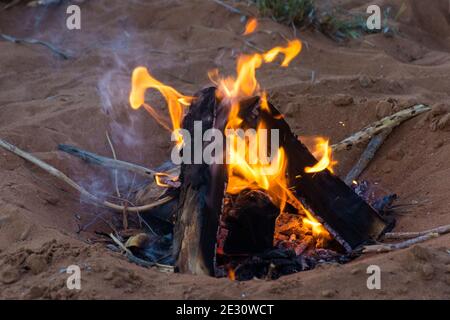 Primo piano di un fuoco di campo nelle dune di sabbia del centro-est per il campeggio di famiglia e ricordi di notte. Foto Stock