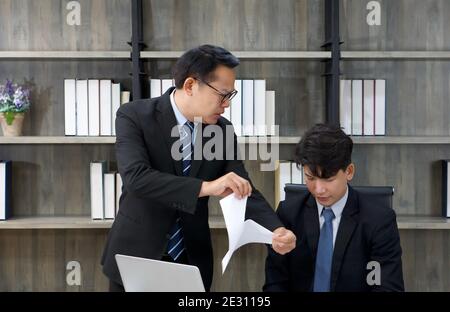 Il manager asiatico ha incolpato il personale e ha strappato i documenti separatamente. Atmosfera di lavoro mattutina in un ufficio moderno. Foto Stock