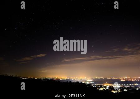 città con molte luci nel cielo notturno e stellato Foto Stock