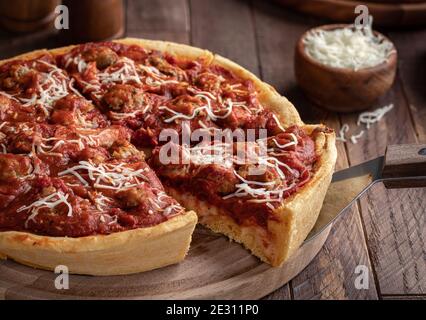 Fetta di pizza a base di salsiccia su un piatto di legno Foto Stock