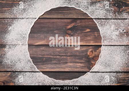 Farina sparsa in forma di cerchio su un vecchio sfondo di legno. Posiziona per il testo. Sfondo per la cottura. Foto Stock