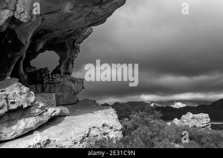 Una colonna di arenaria, situata a formare una finestra naturale nella regione delle grotte di Stadsaal delle montagne di Cederberg in Sud Africa, con il sole che si infrangono Foto Stock