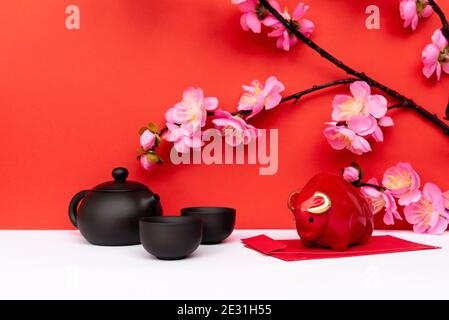 Anno di Ox Piggy Bank, Sakura Cherry Blossom, Black Chinese Teapot e Red Envelope Angpoow su bianco e Red Chinese New Year background Foto Stock