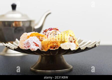 Closeup asorti di dolci orientali in un vaso di metallo basso su un tavolo scuro. Messa a fuoco superficiale. Foto Stock