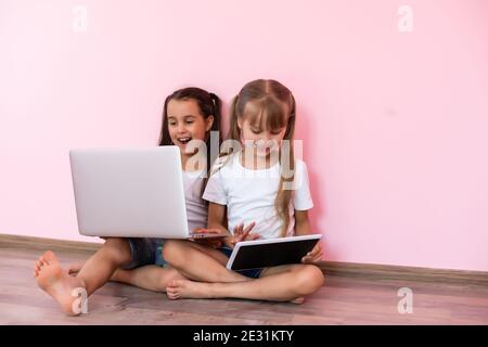 Stupite bambine che mostrano una t-shirt bianca, isolate su sfondo rosa. Concetto di stile di vita infantile. Spazio di copia fittizio. Punta del dito indice Foto Stock