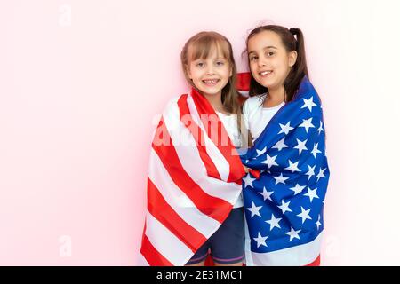 Stupite bambine che mostrano una t-shirt bianca, isolate su sfondo rosa. Concetto di stile di vita infantile. Spazio di copia fittizio. Punta del dito indice Foto Stock