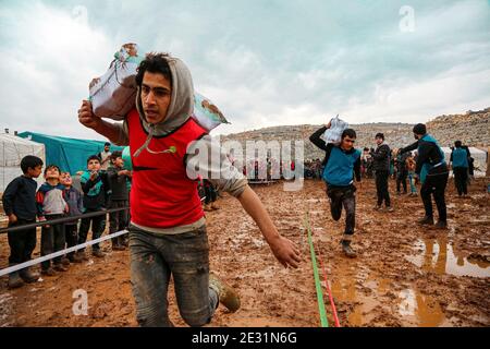 Idlib, Siria. 16 gennaio 2021. Gli attivisti giocano con i bambini nel fango del campo di Baraem Abu al Feda. Attivisti nella campagna dell'Idlib hanno organizzato un evento di intrattenimento per portare gioia ai bambini e dimenticare le loro sofferenze, le attività si sono svolte nel campo di Baraem Abu al Feda, a ovest della città di 'armada'. Le attività includono il calcio, la pittura e il gioco nel fango. Credit: SOPA Images Limited/Alamy Live News Foto Stock