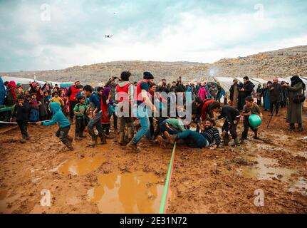 Idlib, Siria. 16 gennaio 2021. Gli attivisti giocano con i bambini nel fango del campo di Baraem Abu al Feda. Attivisti nella campagna dell'Idlib hanno organizzato un evento di intrattenimento per portare gioia ai bambini e dimenticare le loro sofferenze, le attività si sono svolte nel campo di Baraem Abu al Feda, a ovest della città di 'armada'. Le attività includono il calcio, la pittura e il gioco nel fango. Credit: SOPA Images Limited/Alamy Live News Foto Stock