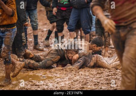 Sarmada, Siria. 16 gennaio 2021. I bambini siriani lottano nel fango durante un concorso sportivo organizzato da volontari nel campo di Baraem per sfollati interni. Credit: ANAS Alkharboutli/dpa/Alamy Live News Foto Stock