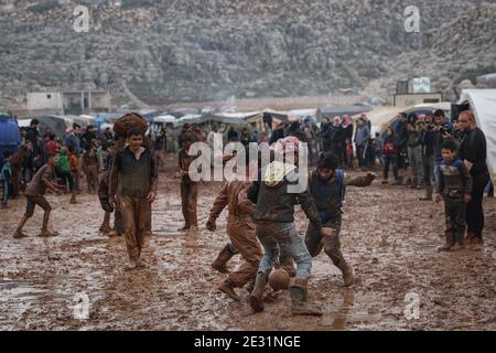 Sarmada, Siria. 16 gennaio 2021. I siriani giocano a calcio nel fango durante una competizione sportiva organizzata da volontari nel campo di Baraem per sfollati interni. Credit: ANAS Alkharboutli/dpa/Alamy Live News Foto Stock