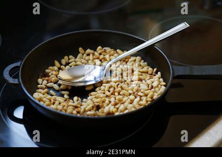 Pinoli arrosto in una padella di ghisa Foto Stock