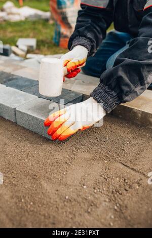 Lavorazione calcestruzzo e posa pietra per pavimentazione - finitura esterna di il sito vicino alla casa - sostituzione di asfalto Foto Stock