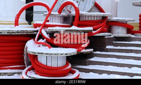 Grandi bobine di tubo corrugato flessibile rosso utilizzate per proteggere i cavi negli impianti elettrici. Un sacco di tubo flessibile in plastica di polietilene colorato utilizzato in contro Foto Stock