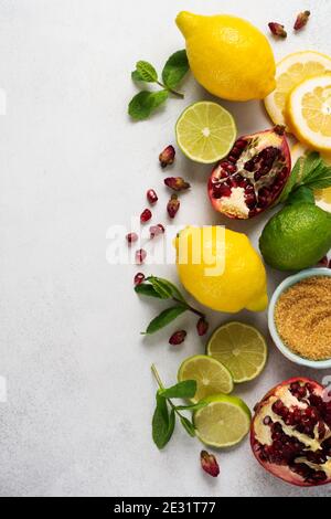 Limone fresco, lime, melograno, fiori di rosa di tè secco, tè, zucchero di canna e foglie mazzo di menta su sfondo grigio. Ingredienti per la produzione della limonata dr Foto Stock