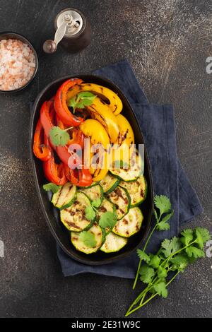 Verdure grigliate pezzi di zucchine, pepe rosso e giallo e bouquet di coriandolo sul piatto, insalata su griglia griglia barbecue rack sopra carbone. Vista dall'alto. Barbec Foto Stock