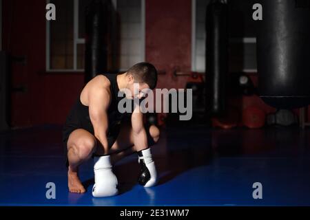 Combattente kickboxing in guanti di pugilato in piedi su ginocchia. Foto di alta qualità Foto Stock