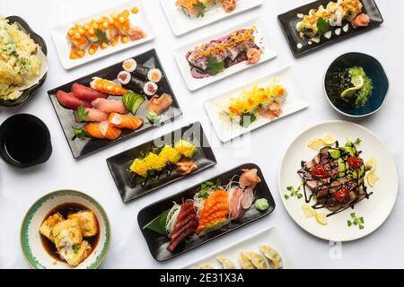 Cucina giapponese tradizionale vista dall'alto su sfondo bianco, Sushi, Sashimi, tofu, Gyoza. Foto Stock