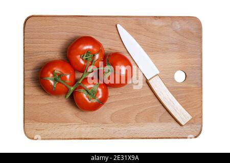 Pomodoro fresco e coltello in ceramica sul tagliere della cucina isolato su bianco Foto Stock
