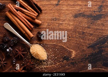 Cannella naturale assortita, zucchero di canna, caffè macinato, anice stelle cottura ingredienti su uno sfondo marrone rustico. Foto Stock