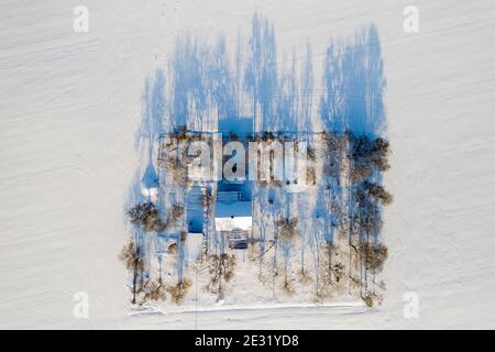 Casa solitaria nel mezzo di un campo innevato vista dall'alto. Foto Stock