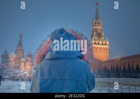 Mosca, Russia. 16 gennaio, 2021 persone camminano sulla Piazza Rossa sullo sfondo della torre Spasskaya del Cremlino di Mosca e della Cattedrale di San Basilio durante la caduta di temperatura a -15°C (5°F) e la nevicata nel centro di Mosca, Russia Foto Stock