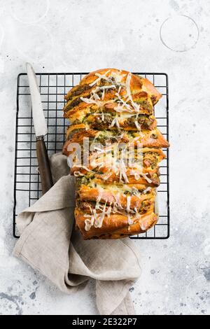 Pane a strappo con pesto di pasta italiana, basilico e parmigiano in forma di cottura su vecchio fondo di cemento chiaro. Vista dall'alto. Stile rustico. Foto Stock