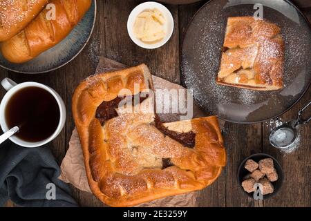 Torta di mele, panini freschi e tè su sfondo di legno marrone. Foto Stock