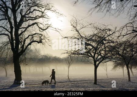 Una donna e il suo cane fare una passeggiata lungo il foggy sentiero di vagabando Rein ad Harrogate in una gelida mattina d'inverno, North Yorkshire, Inghilterra, Regno Unito. Foto Stock