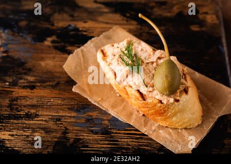 Sandwich con pate di pollo con cappero su un vecchio sfondo scuro della tavola. Messa a fuoco selettiva Foto Stock