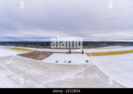 Ampia vista aerea invernale su campi innevati con alberi e un orizzonte nuvoloso, sparato da un drone. Foto Stock