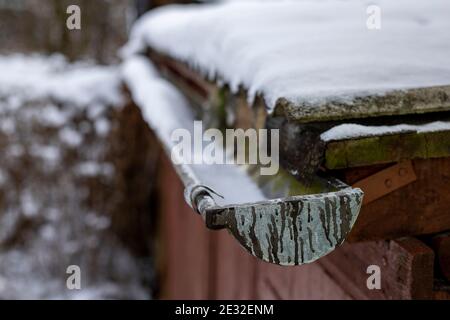 Una grondaia coperta di neve sul tetto. Neve che giace sul tetto e grondaia per il drenaggio. Stagione invernale Foto Stock
