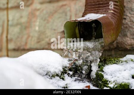 Gutter ghiacciato in una casa singola. Ghiaccio nel gocciolatoio di drenaggio. Stagione invernale. Foto Stock